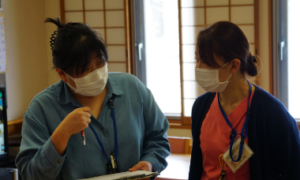 マスク着用の職員2名が室内で打ち合わせまたは指導を行っている様子