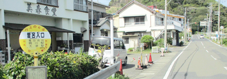 施設周辺の道路と入口看板。建物と外構が見える